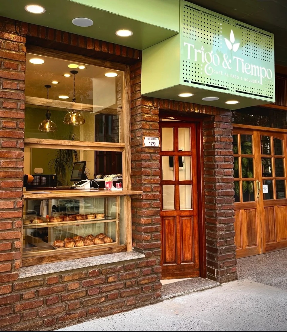 Fachada de Trigo & Tiempo con cartelería verde y paredes de ladrillo.