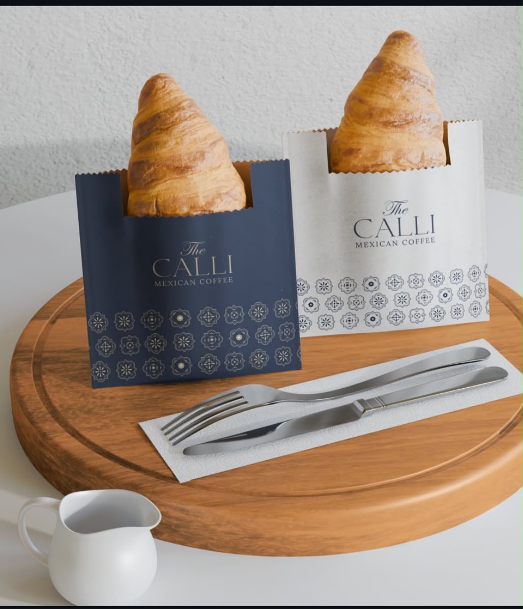 Bolsas de The Calli con croissants sobre una mesa de madera.